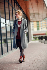 Obraz premium Beautiful and young girl in a coat and scarf and sunglasses walking around the city in the summer.