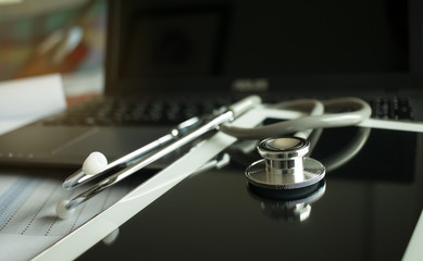 Fototapeta na wymiar Stethoscope on screen tablet, laptop computer at medicine doctor work, selective focus, classic tone