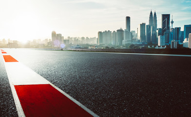 Racetrack with red and white safety sideline ,modern city background ,dramatic cloudy sky and...