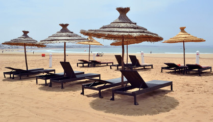 Sand beach with sun loungers and parasols from the sun