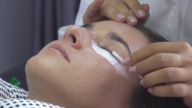 Professional master remove oil with cotton bud from models eye. Preparation before eyelash extension in beauty studio.