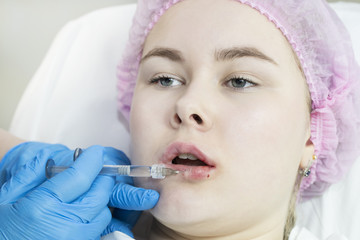 The process of cosmetic surgery of water injection in the area of the lips of a woman 
