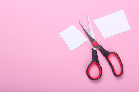 Scissors Cut The Paper In Half On A Pink Background