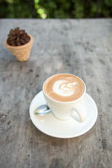 Cup of hot latte art coffee on wooden table.