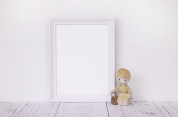 Fototapeta na wymiar Stock photography of retro white frame template vintage wood table and cute ceramic doll