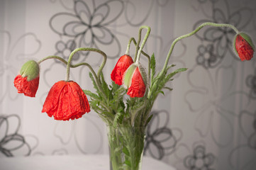A beautiful bouquet of red poppies in a vase on blurred background