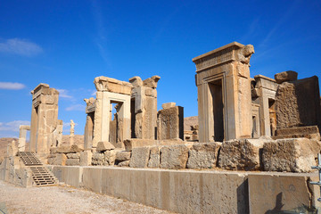 Obraz premium Ruins of Apadana and Tachara Palace behind stairway with bas relief carvings in Persepolis UNESCO World Heritage Site against cloudy blue sky in Shiraz city of Iran.