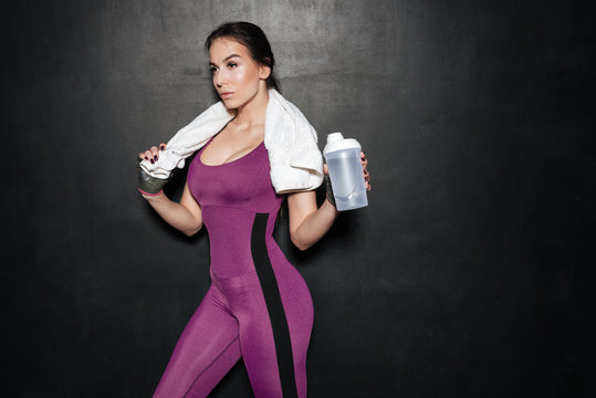 Sporty young woman in tracksuit with towel and water bottle