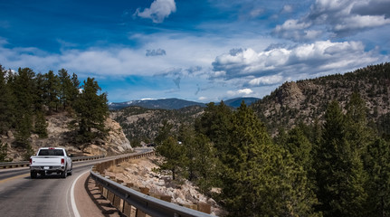 White pickup, driving, traveling in the mountain road, highway. Blue HDR sky background, green...