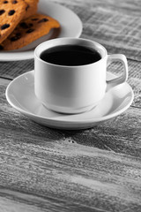 cup of coffee with a brown cookie on a wooden table