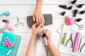 Manicure for the client. Close-up of the hands of a manicurist and client on a wooden background