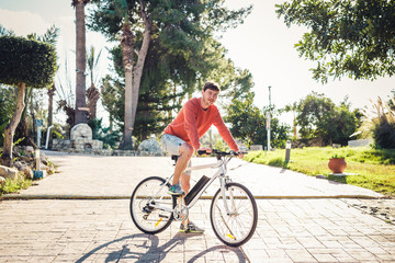 Portrait of handsome guy riding bicycle in the park