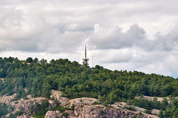 Obraz premium Radio communication tower rising up through the trees in the woods on the cliffs in Stavanger, Norway