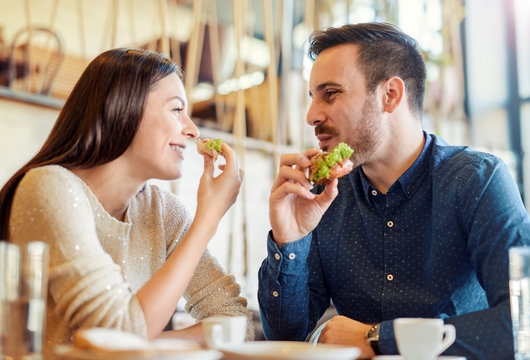 Beautiful young couple sitting in a cafe, having breakfast. Love, romance, relationships, food, lifestyle