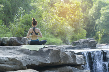 young women practicing yoga in nature near waterfall relax time.
