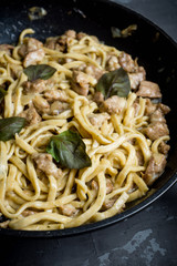 Fresh homemade fettuccini pasta with meat, cheese and basil on the black rustic background