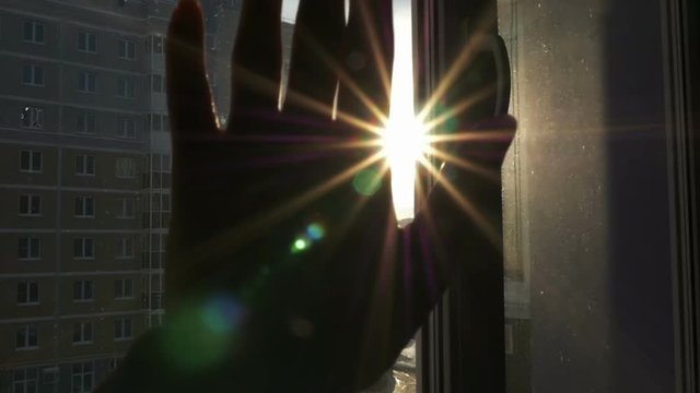 The female hand touches the sun and plays with the sun's rays