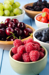 Fresh Fruit in Separated Bowls on Light Blue Wood Planked Table
