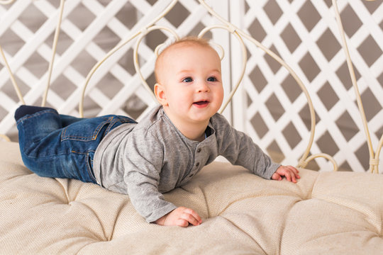 Adorable laughing baby boy in sunny bedroom. Newborn child relaxing. Family morning at home. Little kid lying on tummy