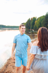 Young beautiful couple in love walking on the beach on sunset.