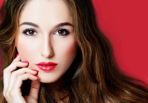 Beautiful woman face closeup image. Perfect makeup with red lipstick and nails. isolated on red background. 