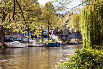 Naklejka premium Amsterdam canal view with small boats. Spring day in the city