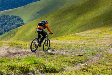 A man is riding bicycle, on the background of mountains. Beautiful summer day.