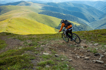 Obraz premium A man is riding bicycle, on the background of mountains. Beautiful summer day.