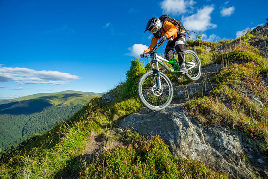 A man is riding bicycle, on the background of mountains and blue sky. Beautiful summer day. © Taras