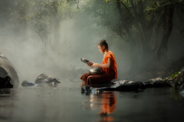 Thailand Little monk sitting on the creek or river in forest at Countryside Thailand of Buddhism,...