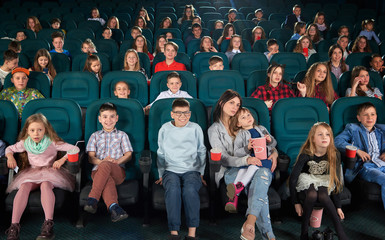 Full length shot of a woman enjoying watching a movie at the cinema with her little daughter in an...