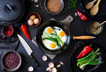 Fried eggs in a dark frying pan, top view