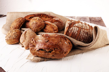 Different kinds of bread and bread rolls on board from above. Kitchen or bakery poster design.