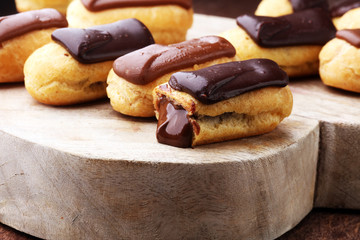 Traditional French dessert. Eclair with chocolate icing. Wooden background