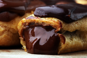 Traditional French dessert. Eclair with chocolate icing. Wooden background