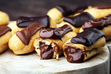 Traditional French dessert. Eclair with chocolate icing. Wooden background