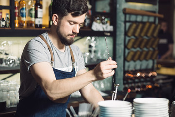 Young male bartender preparing an alcohol cocktail