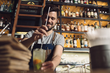 Young male bartender preparing an alcohol cocktail