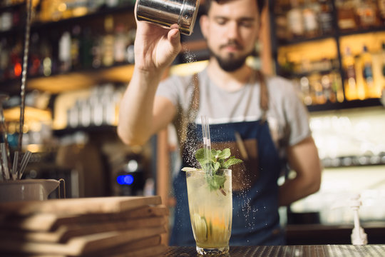 Young male bartender preparing an alcohol cocktail