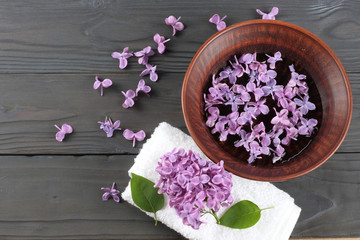 Obraz na płótnie Canvas spa lilac flower in water on wood background