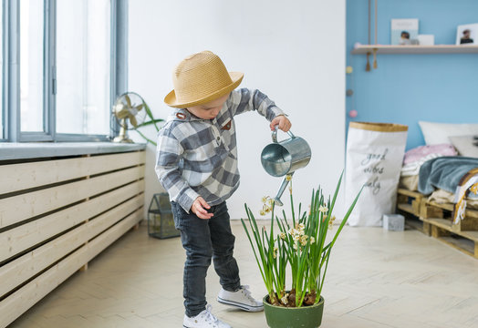 Cute Boy In Straw Hat With A Watering Can. Watering Plant