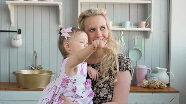 Positive young mother holding her baby in the kitchen at home