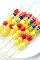 Fresh fruit on skewers on a white wooden table
