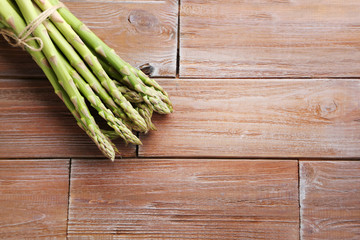 Heap of green asparagus on brown wooden table