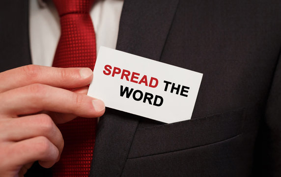 Businessman putting a card with text Spread the word in the pocket