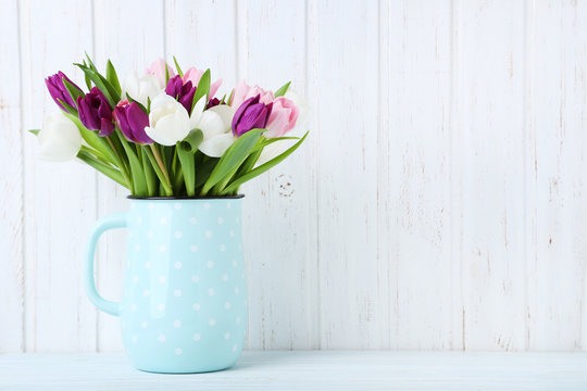 Bouquet of tulips in jug on a wall paneling background