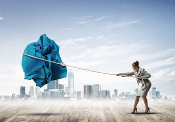 Woman pulling with effort big crumpled ball of paper as creativity sign © adam121