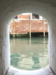 вид на морскую воду венецианского канала и противоположное старое здание через арочный проем