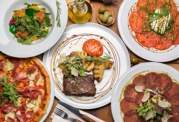 delicious Italian food on a nearby table with Cutlery and a bottle of olive oil