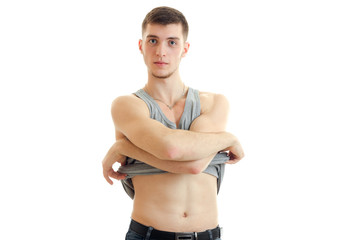 young serious guy looks right and takes off shirt